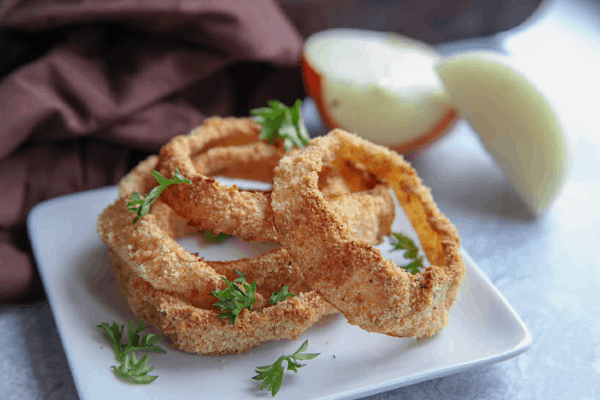 Crispy brown air fryer onion rings on a white plate