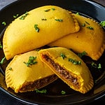 four jamaican beef patties on a plate