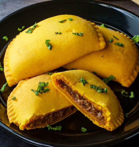 four jamaican beef patties on a plate