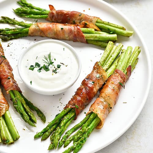 asparagus wrapped in bacon on a white plate