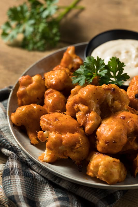 cooked cauliflower wings on a plate with dipping sauce