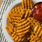 cooked waffle fries on a plate with ketchup