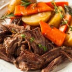 roast beef on a plate with carrots and potatoes