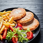 cooked turkey burgers on a plate with fries and salad