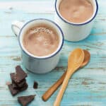 hot chocolate in mugs with spoons and chocolate