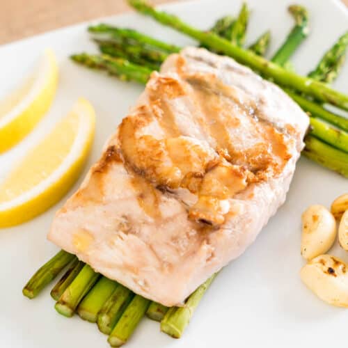 cooked snapper on a plate with asparagus