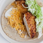 breaded chicken on a tortilla with lettuce, cheese, and ranch