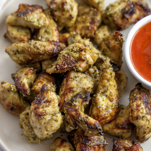 bite sized pieces of pesto chicken on a plate with marinara sauce