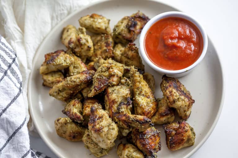 bite sized pieces of pesto chicken on a plate with marinara sauce