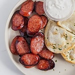 sliced smoked sausage on a plate with pierogies and sour cream